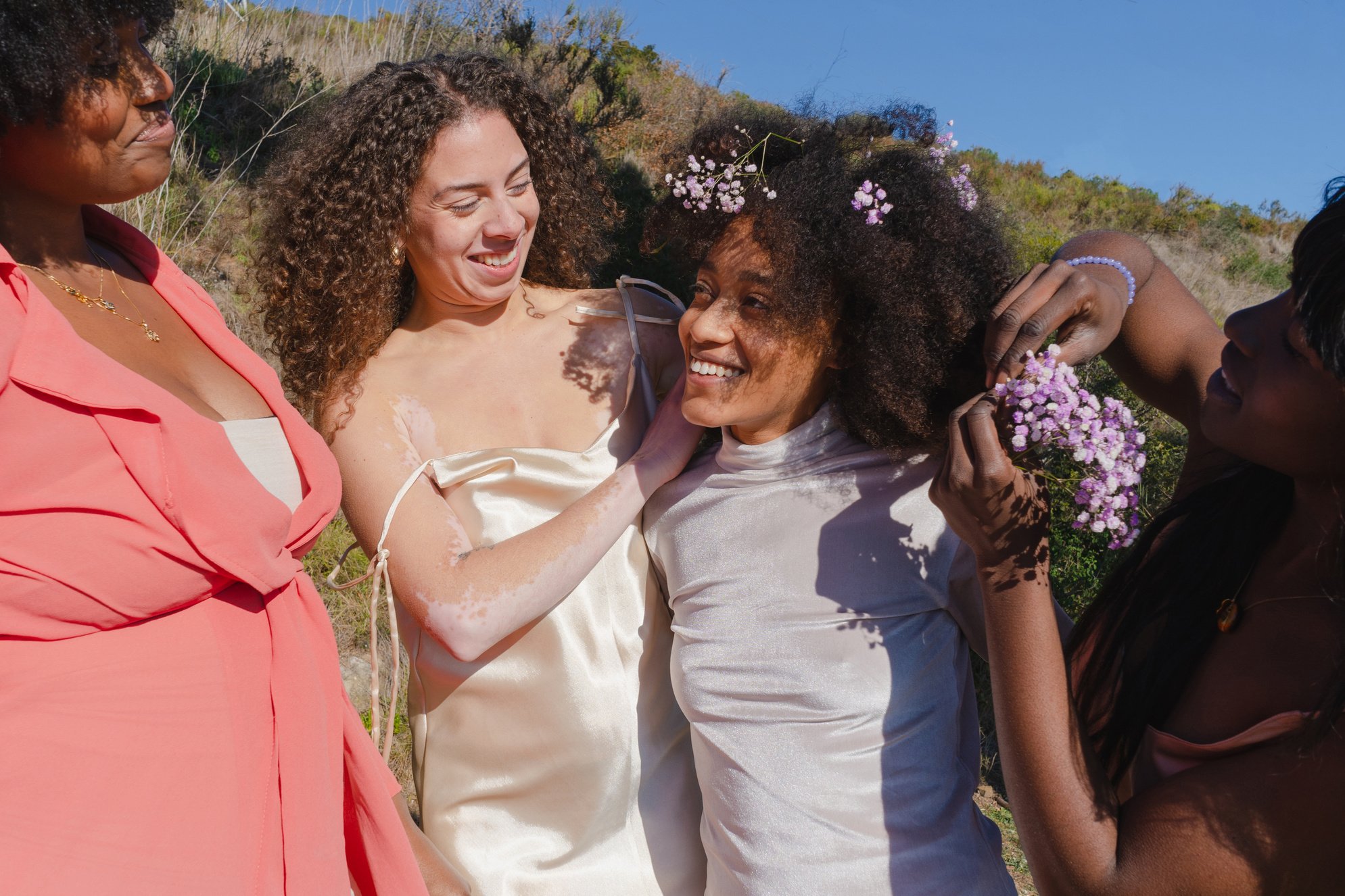 Women Putting Flowers in Woman's Curly Hair